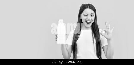 Zwinkern Kind halten Milchgetränk Produkt. Teen Mädchen gehen, um Milch zu trinken. Horizontales Poster mit isoliertem Kindergesicht, Banner-Header, Kopierbereich. Stockfoto