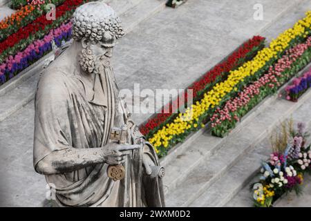 Vatikanstadt, Italien 31.03.2024: Statue des heiligen Petrus mit Blumen als Hintergrund. Papst Franziskus führt den Ritus der Ostermesse in der Kirche Stockfoto