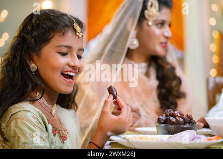 Glücklich aufgeregt indische Mädchen essen Dates während des Ramadan iftar Abendessen oder Abendessen mit der Familie - Konzept der gesunden Ernährung, ramzan iftar und Stockfoto