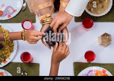 Foto von oben von indischem Ehemann mit Kindern, die während des ramadan-Festes zu Hause Daten von muslimischen Frauen nehmen - Konzept von Ramadan-Festmahl, iftar und Bindung Stockfoto