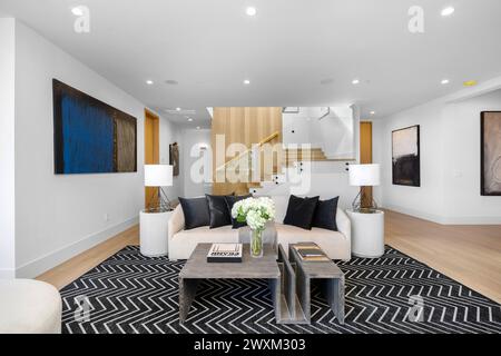 Ein geräumiges Wohnzimmer mit einem großen weißen Sofa und zwei Couchtischen. Stockfoto
