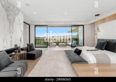 Ein Schlafzimmer mit einem Bett, einer Couch und weitläufigen Fenstern an der Wand. Stockfoto