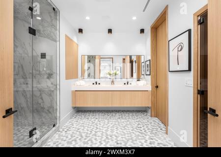 Modernes Badezimmer mit Holzschränken und Doppelwaschbecken in weiß und Beige. Stockfoto
