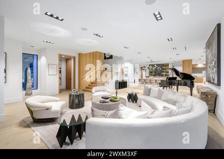 Ein weißes Sofa, zwei schwarze Stühle und ein Klavier im Zimmer. Stockfoto
