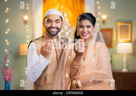 Glückliches indisches muslimisches Paar, das sich das ramadan-Festival wünscht, indem es mit der Hand sagt, indem es in die Kamera schaut - Konzept des islamischen Festivals, Zweisamkeit Stockfoto