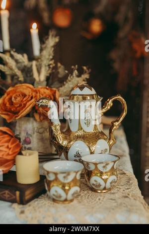 Ein Tisch mit alten Kaffeetassen, Untertassen und goldenen Teekanne Stockfoto