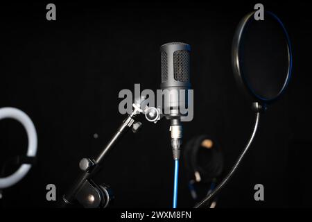 Nahaufnahme eines professionellen Kondensatormikrofons auf schwarzem Hintergrund in einem Musikstudio. Stockfoto