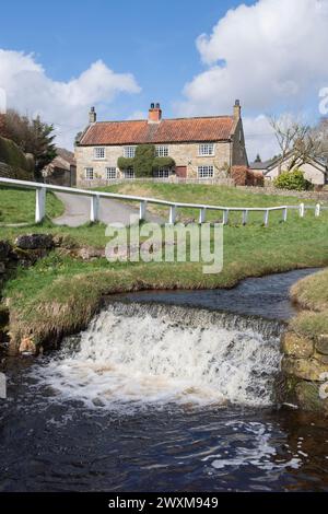 Ein traditionelles Steinhaus am Fluss im malerischen Dorf Hutton-le-Hole im North York Moors National Park Stockfoto