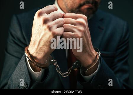 Handschellen verhafteter Geschäftsmann, Nahaufnahme eines Mannes im Geschäftsanzug mit Handschellen, selektiver Fokus Stockfoto