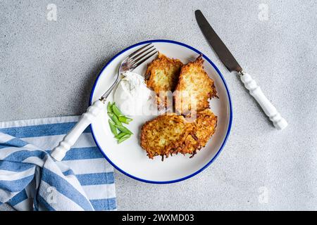 Kartoffelpfannkuchen auf dem Teller mit Sauerrahm serviert Stockfoto