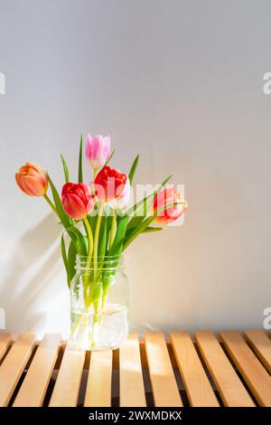 Farbenfrohe Frühlingstulpen im Glasgefäß Stockfoto