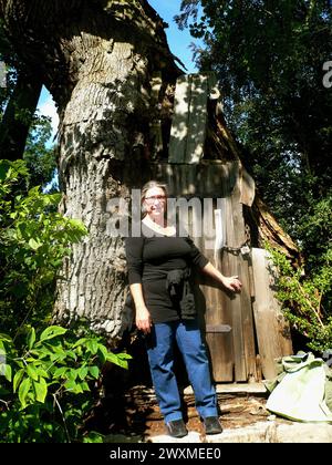 Alte Eiche auf der Pfaueninsel mit einer Eingangstuer, vor der Frau steht Frau lehnt an einem Baum mit Tuer *** Alte Eiche auf der Pfaueninsel mit einer Eingangstür, vor der eine Frau steht, die sich an einen Baum mit einer Tür lehnt Stockfoto