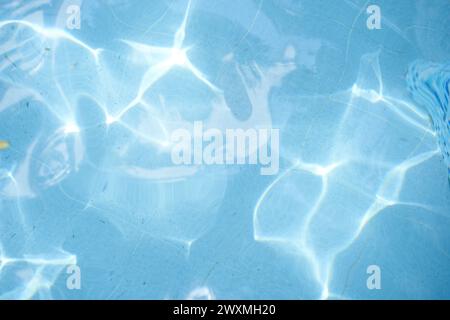 Blick von oben auf den blauen Swimmingpool, Reflexion auf blauem Wasser, Struktur mit Wirbelmuster, blaue Fliesen. Blätter in schmutzigem Wasser, offener Swimmingpool. Hintergrund, Hintergrund mit Kopierraum. Stockfoto