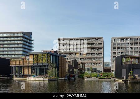 Moderne Wohnhäuser am Kanal in Amsterdam Noord mit schwimmenden Häusern und Grünflächen, die in zeitgenössische städtische Architektur integriert sind Stockfoto