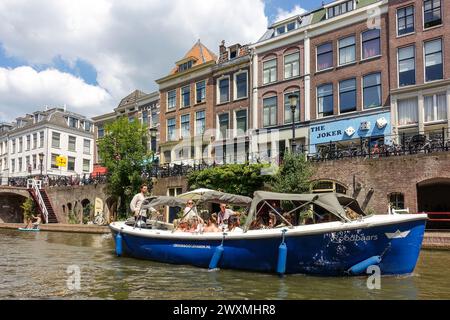 Touristen genießen eine Bootstour auf einem überdachten Boot, vorbei an historischen Gebäuden und Cafés am Wasser in Utrecht, Niederlande Stockfoto