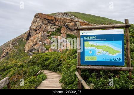 Malerische Aussicht auf das Robberg Nature Reserve mit einem Pfad zu felsigen Klippen und einem Schild mit dem „The Gap“ Wanderweg in Südafrika. Stockfoto