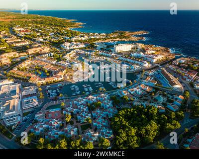 Blick von der Drohne auf den Hafen, die Wohnung und den Strand von Cala en Bosc auf der spanischen Insel Menorca. Stockfoto
