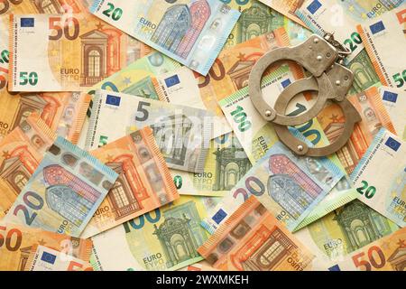 Viele europäische Euro-Geldscheine und Handschellen. Viele Banknoten der Währung der Europäischen union und Handschellen aus nächster Nähe Stockfoto