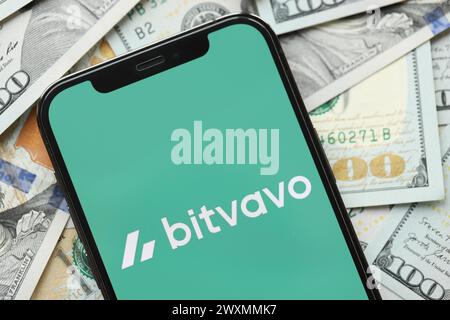 KIEW, UKRAINE - 15. MÄRZ 2024 Bitvavo-Logo auf dem iPhone-Display mit vielen Hundert-Dollar-Scheinen. Portal für den Austausch von Kryptowährungen Stockfoto