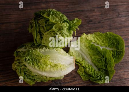 Römischer Salat vor rustikaler Kulisse. Holztisch und grünes Gemüse. Küche und Blätter. Gesunde Ernährung. Stockfoto