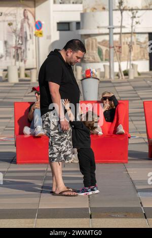 Tel Aviv, Israel - 6. Januar 2023: Ein kleines Mädchen bittet ihren Vater, sie an einem sonnigen Tag in einer Straße in Tel Aviv in Israel abzuholen. Stockfoto