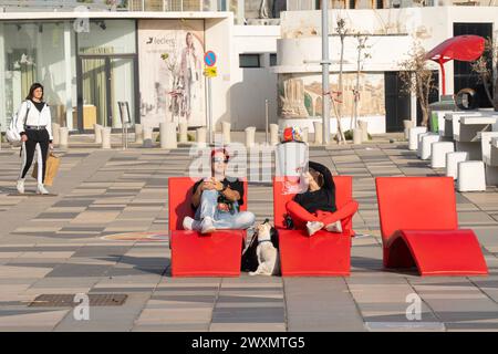 Tel Aviv, Israel - 6. Januar 2023: Ein Mann, eine Frau und ihr Hund, auf roten Stühlen auf einer Straße in Tel Aviv, Israel an einem sonnigen Tag. Stockfoto