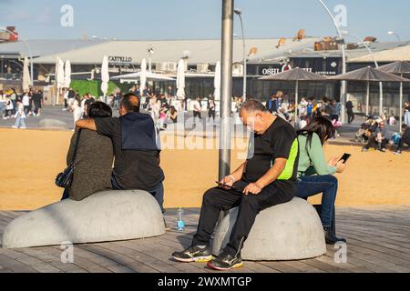 Tel Aviv, Israel - 6. Januar 2023: Zwei Paare sitzen auf Betonbänken im Hafenbereich von Tel Aviv, ein Paar umarmt sich, das andere schaut s an Stockfoto