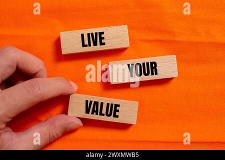 Leben Sie Ihre wertvollen Worte auf Holzblöcken mit orangefarbenem Hintergrund. Konzeptionelles Geschäftssymbol. Kopierbereich. Stockfoto