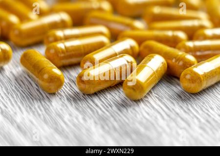 Medikamentengelbe Ergänzungskapseln auf alten Naturbrettern Nahaufnahme. Kräutermedizin, Pharmazie-Konzept Stockfoto