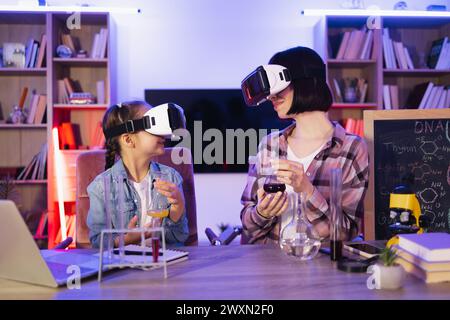 Kaukasische Mutter macht chemische Experimente oder Tests mit kluger süßer Tochter mit Virtual-Reality-Headset. Die sorgende Frau und das kleine Mädchen verbessern sich Stockfoto