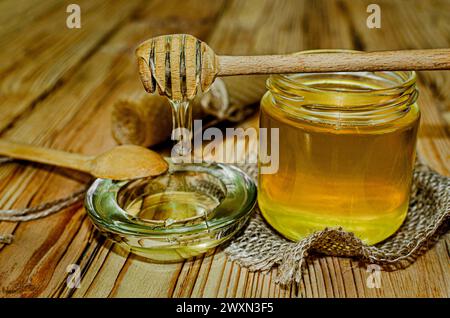 Honig im Glas mit Honiglöffel auf rustikalem Holztischhintergrund. Stockfoto