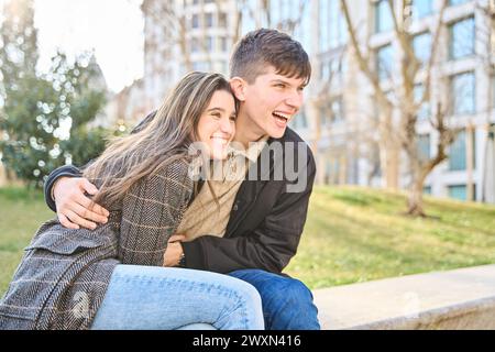 Glückliche Momente in der Stadt, Junges Paar, das Lachen und Freude teilt und in unvergesslichen Momenten auf der Straße sitzt. Stockfoto