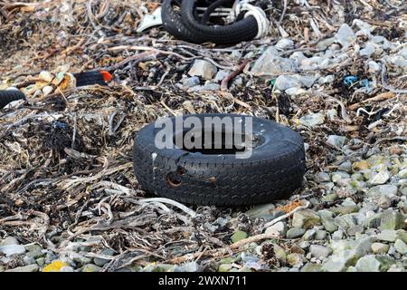 Kunststoffe, Reifen zum Schutz der Seiten von Fischerbooten und andere Abfälle, die an der Küste in der Nähe von Fraserburgh, Aberdeenshire, Schottland, Vereinigtes Königreich, angespült werden. Stockfoto