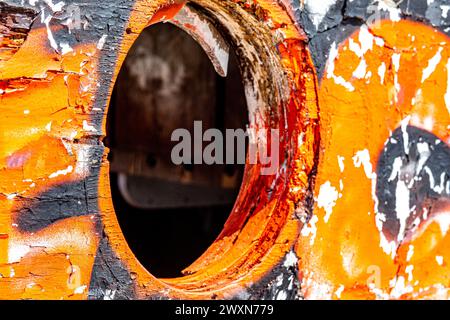 Nahaufnahme des Lochs, in dem das Bullaugenfenster in einem Holzrumpf des alten, beschädigten Bootes war, abblätterte orange, schwarz-weiße Farbe, sonniger Tag am mexikanischen Strand Stockfoto