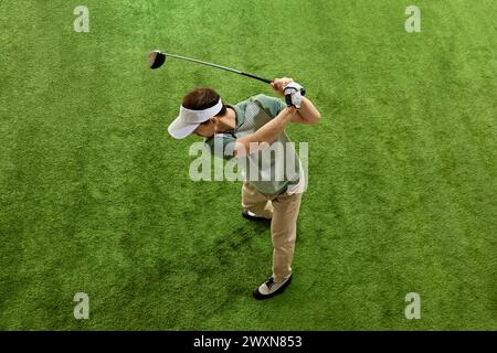 Top-View-Porträt eines männlichen Golfspielers, der sich auf den Golfspieler konzentriert, während er auf Kunstrasen nachverfolgt wird. Stockfoto