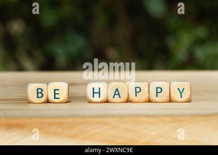 Glückliche kurze Phrase aus hölzernen Buchstabenblöcken auf einem Holztisch Stockfoto