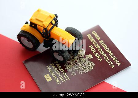 Roter polnischer Pass und gelber Traktor auf glatter rot-weißer Flagge von Polen Nahaufnahme Stockfoto