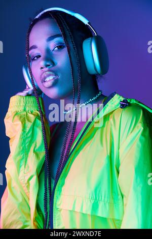 Schöne afroamerikanische Frau im Kopfhörer, die in die Kamera im Studio mit Neonlichtern blickt Stockfoto