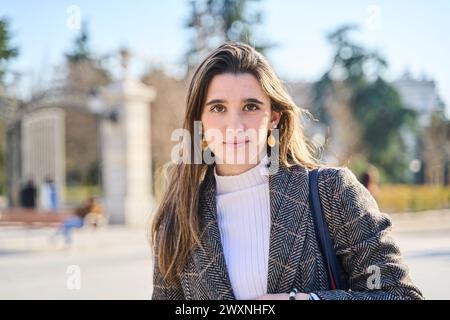 Eine stilvolle junge Frau, die durch einen Stadtpark schlendert und die Herbstbrise mit Grace, Joy und zeitloser Schönheit begrüßt. Stockfoto