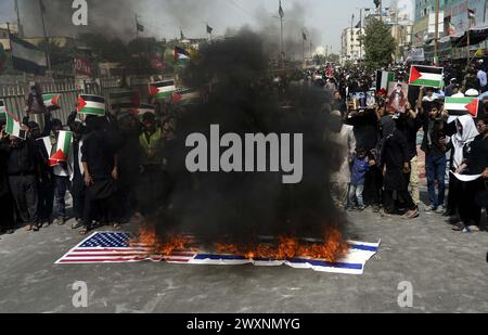 Schiitische Muslime, die Hazrat Ali Al-Murtaza (A.S) trauern, verbrennen die Flagge der USA und Israels, während sie gegen israelische grausame und unmenschliche Handlungen protestieren und die Einheit mit dem unschuldigen Volk Palästinas zum Ausdruck bringen, nachdem sie Salat-e-Zohrain anlässlich des Youm-e-Ali (A.S), dem Tag des Martyriums 21. Ramadan-ul-Mubarak, durchgeführt haben, an der M.A Jinnah Road in Karachi am Montag, 1. April 2024. Stockfoto