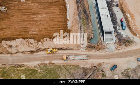 Ein Schotterfeld mit gelben Bussen und LKWs, die nebeneinander geparkt sind Stockfoto