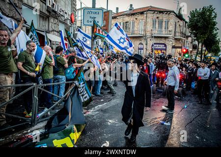 Jerusalem, Israel. 31. März 2024. Eine ultra-orthodoxe jüdische Jugend singt Demonstranten während einer Demonstration an. Dutzende Demonstranten der Brothers in Arms-Bewegung veranstalteten eine Demonstration in Jerusalems ultra-orthodoxem Viertel MEA Shearim und forderten, dass die Gemeinde bei der IDF eingezogen wird. Sonntag war die Frist für die Regierung gewesen, Gesetze zur Lösung des Problems zu erarbeiten, aber Netanjahu reichte in letzter Minute einen Antrag beim Obersten Gerichtshof auf ein 30-tägiges Moratorium ein. Quelle: SOPA Images Limited/Alamy Live News Stockfoto