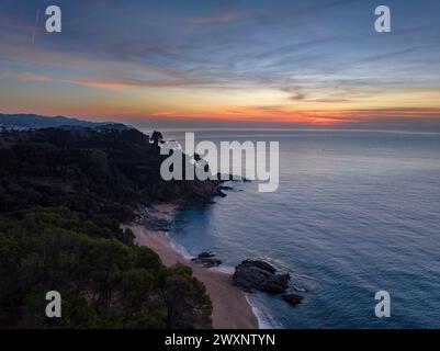 Luftaufnahme der Bucht Sa Boadella in Lloret de Mar bei einem roten Wintersonnenaufgang an der Costa Brava (La Selva, Girona, Katalonien, Spanien) Stockfoto