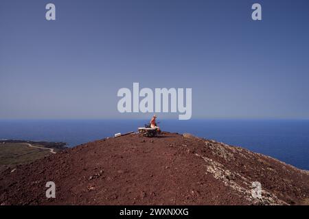 Eine Frau mit Hut, die von der Spitze des Vulkans aus das Meer blickt, genannt Monte Nero, Linosa. Sizilien. Italien Stockfoto