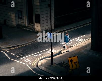 London – 19. Juli 2020 – Straßenfotografie eines Menschen, der mit dem Schaft des Sonnenlichts in den Schatten geht, London, Großbritannien Stockfoto