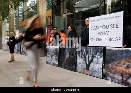 Oktober 2023. Standard Chartered Bank Offices, City of London, UK. Demonstranten der Money Rebellion zeigen eine Ausstellung mit Fotos von Gideon Mendel. Die Pop-up-Ausstellung ist ein Widerspruch zur Standard Chartered Bank, die erneut den Wettbewerb „Wetterfotograf des Jahres“ sponsert. Diese Greenwashing-Übung fängt das dramatische Spektakel extremer Wetterereignisse weltweit ein, lässt aber die Rolle der Bank bei ihrer Entwicklung völlig außer Acht. Oft werden diese fesselnden Schnappschüsse auch nicht in größeren Ruinenszenen kontextualisiert, was darauf hindeutet, dass extremes Wetter schön ist, subli Stockfoto