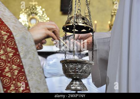Der Priester nimmt Unsinn aus dem Gefäß und legt ihn in das Duldstück, um am Altar dargebracht zu werden, wo sich das Allerheiligste befindet, um verehrt zu werden Stockfoto