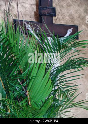 Mehrere grüne Zweige bedecken das Bild Jesu am Kreuz, am Palmensonntag, dem Beginn der Karwoche für Katholiken. Stockfoto