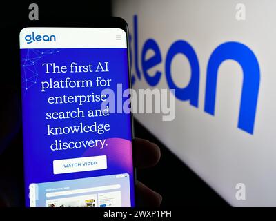 Person, die ein Smartphone hält und die Webseite des US-amerikanischen KI-Assistenten GLean Technologies Inc. Vor dem Logo zeigt. Konzentrieren Sie sich auf die Mitte des Telefondisplays. Stockfoto