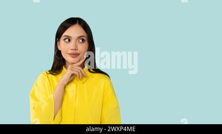 Neugierig aufgeregte junge lateinfrau, die auf einem Kopierraum für Werbung auf blauem Atelierhintergrund steht Stockfoto